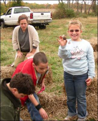 Children search through bales of hay for vegetables.